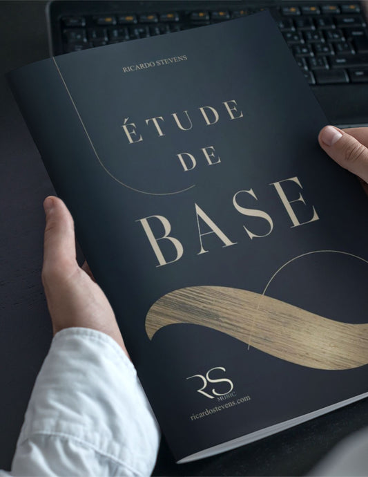 Book titled 'Étude de Base' by Ricardo Stevens held by a person with a keyboard in the background.